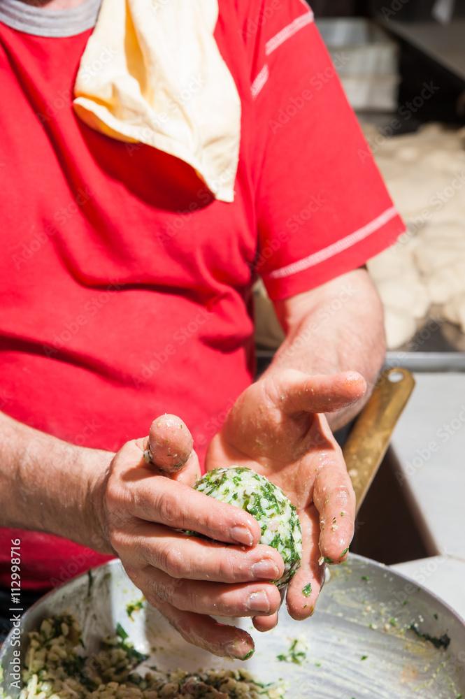 Hands of cook modelling a typical sicilian rice arancino in a cone shape