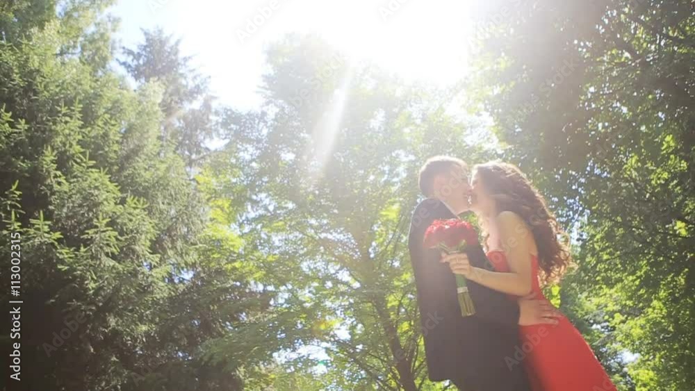 An elegant red dress wedding couple standing in the park in summer An elegant red dress wedding couple standing in the park in summer