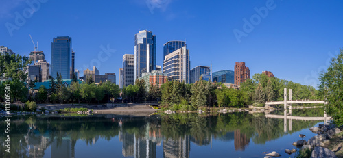 Foot bridge reflected in the Bow River at princes island park and the urban skyline in Calgary Alberta.