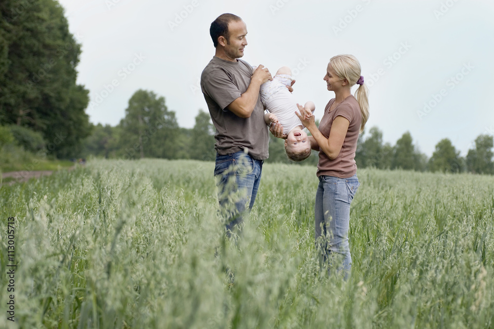Two parents playing with their daughter in a field Two parents playing with their daughter in a field