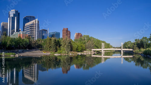 Foot bridge reflected in the Bow River at princes island park and the urban skyline in Calgary Alberta. © Jeff Whyte