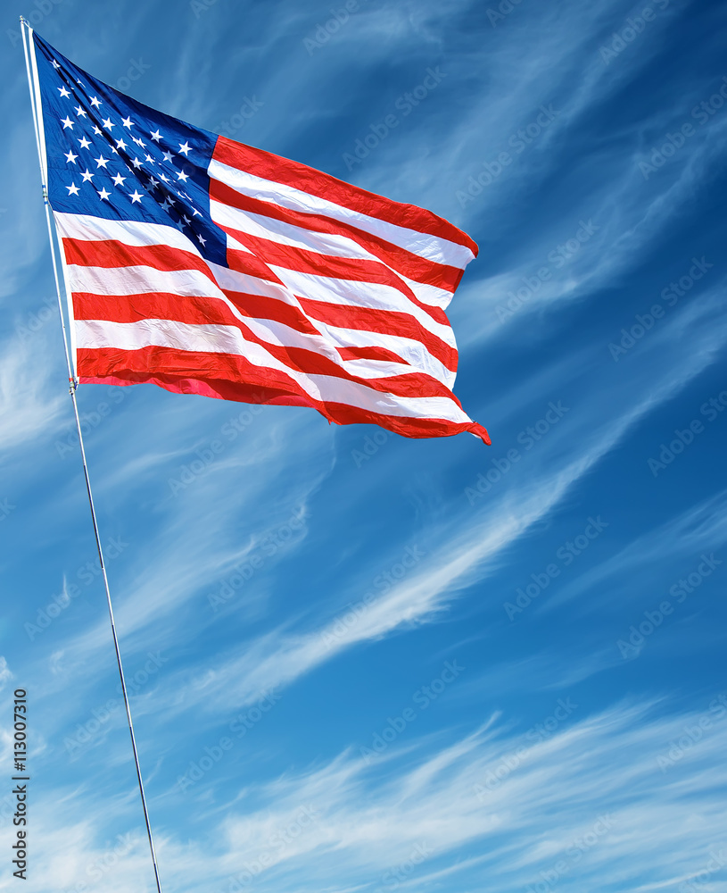 Fototapeta premium American flag waving in blue sky vertical image