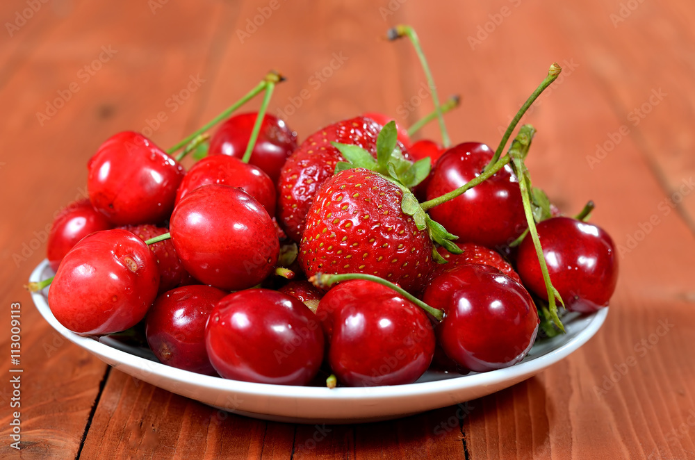 Juicy strawberries and cherries close-up on the old wooden backg Juicy strawberries and cherries close-up on the old wooden backg