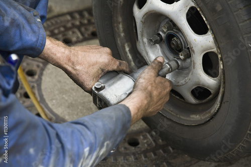 Close-up of mechanic's hands unscrewing a car wheel