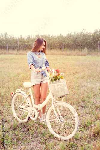 happy cycling moments: portrait of beautiful brunette young woman having fun with bicycle on green summer outdoors copy space background