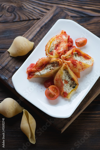 Baked conchiglioni with cottage cheese, rustic wooden setting