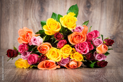 Mixed color roses on wooden background