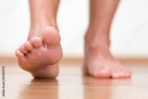 Healthy male feet stepping over home-like background © koszivu