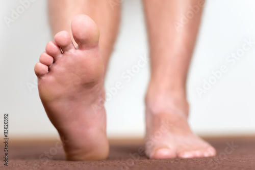 Pair of clean male feet without any illness making a step. © koszivu