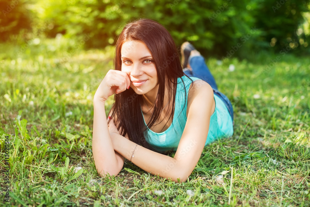 Fototapeta premium Beautiful woman relaxing outdoors on grass looking happy and smiling.
