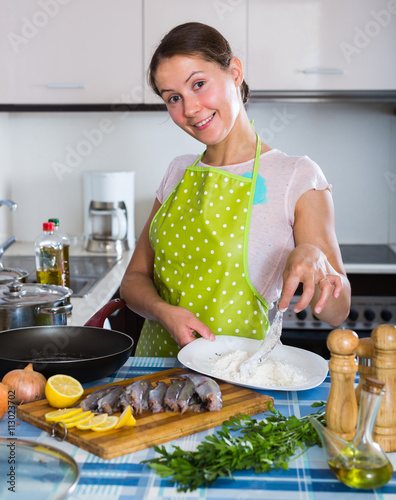 Housewife frying fish at kitchen. photo