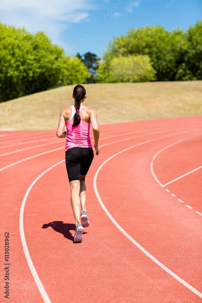 Rear view of female athlete running on the running track