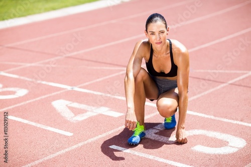 Portrait of female athlete kneeling on running track © WavebreakmediaMicro
