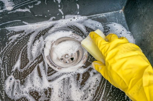 Housework concept. Person is cleaning granite sink in kitchen with rag.