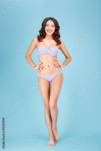 Young beautiful woman in purple swimsuit over blue background