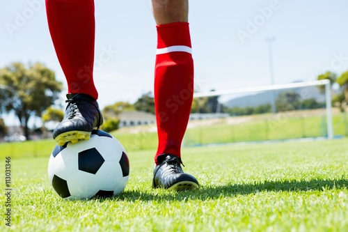 Football player standing with his feet on ball