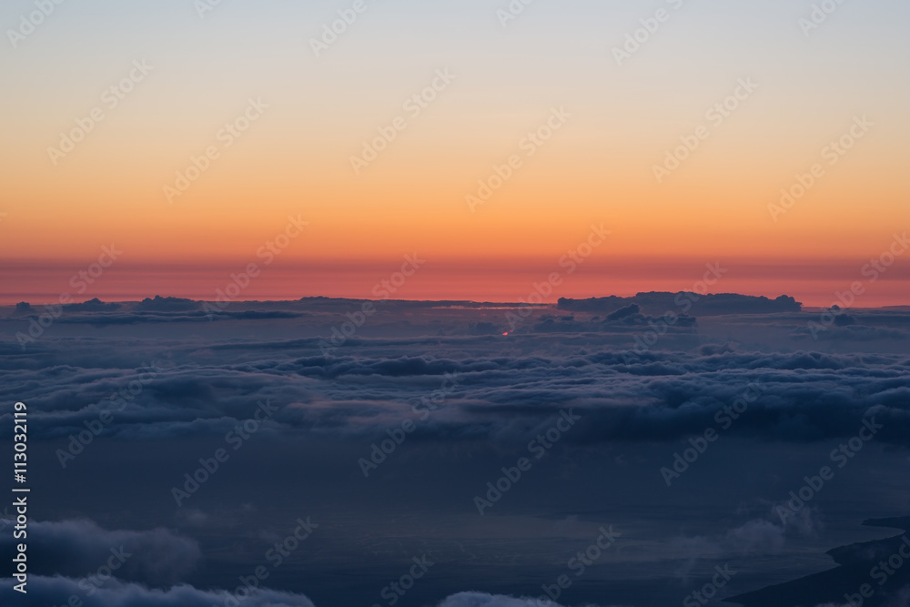 Blue clouds and a red horizon. The sun is below the horizon. The dark coastline is visible on the lower part of the frame