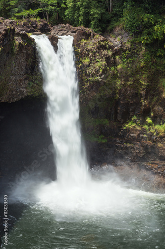 Rainbow Falls rushes into a large pool. The waterfall flows over a lava cave