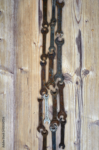 Set of old spanners. Rough spanners on wooden background. Frame of metallic tools 