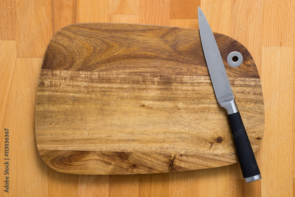 Knife on wooden cutting board on wooden background