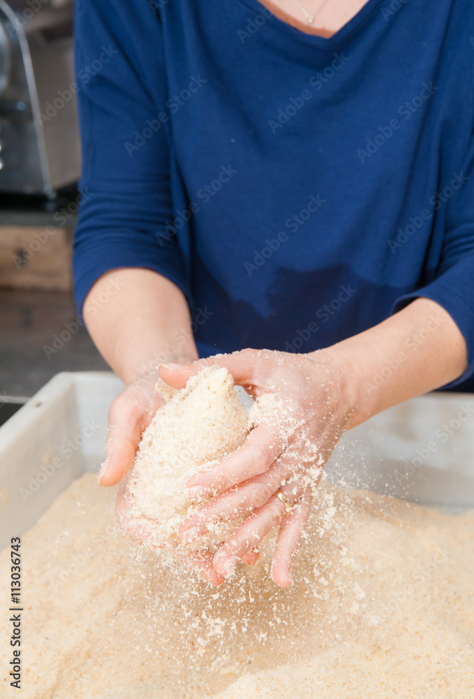 Sicilian cook covering a typical rice arancino with bread crumbs before frying it