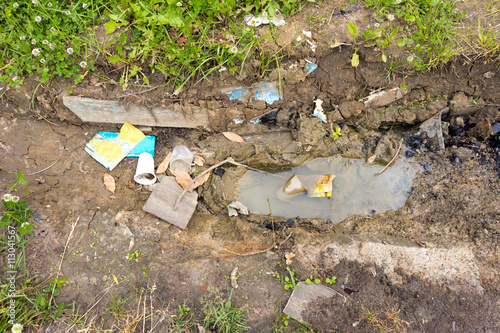 Waste lying on the ground next to the puddle. The dirt brown col photo