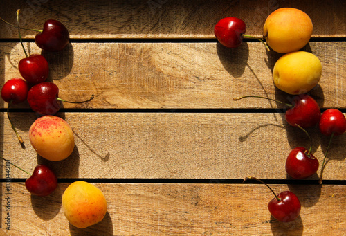 Wooden background with cherries and apricots photo