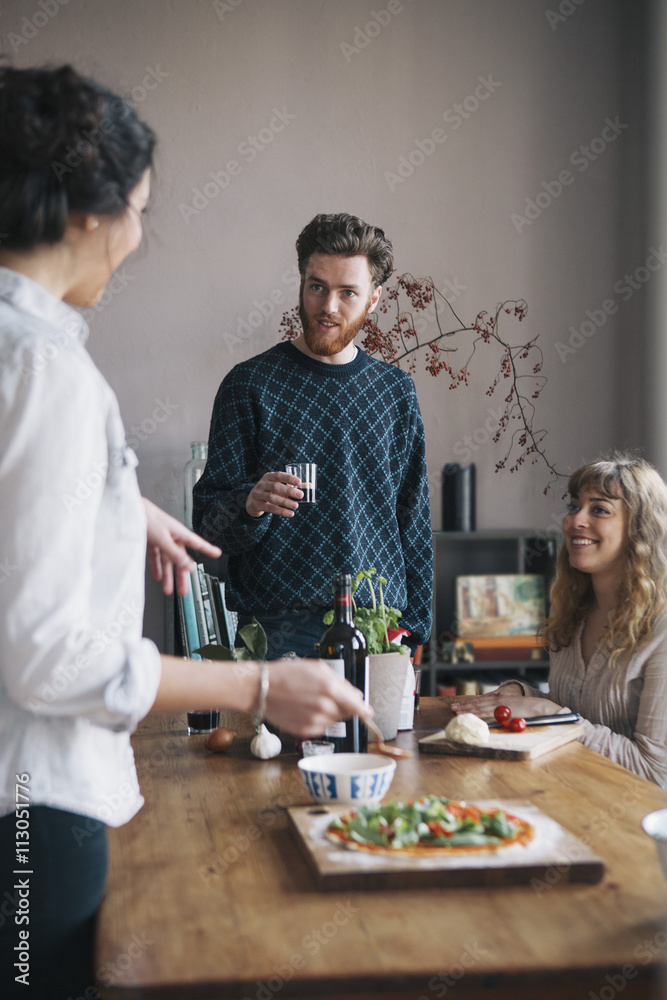 Young man with female friends talking while having breakfast at home Young man with female friends talking while having breakfast at home