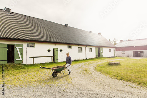 Woman pushing wheelbarrow in farm photo