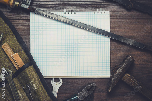 construction tools and blank notepad on the wooden background photo