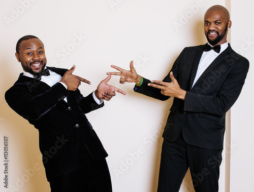 two afro-american businessmen in black suits emotional posing, gesturing, smiling. wearing bow-ties photo