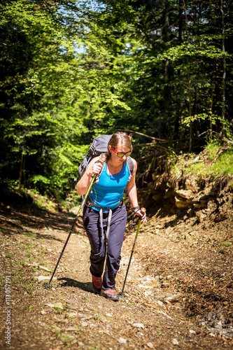 Young female hiker with backpack and hiking poles.