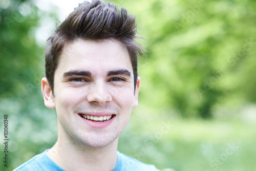 Outdoor Head And Shoulders Portrait Of Smiling Young Man