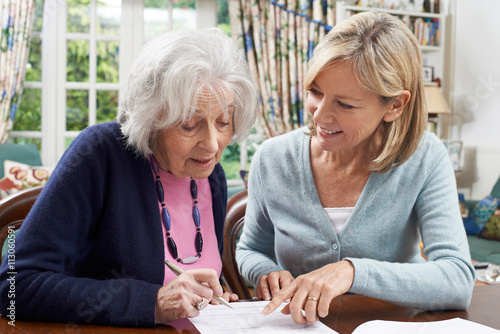Female Neighbor Helping Senior Woman To Complete Form photo
