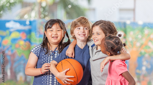 Group of mixed race children playing basketball in school courty