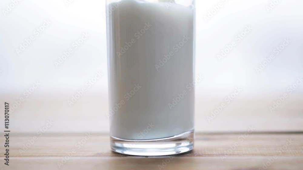 hand pouring milk into empty glass on wooden table hand pouring milk into empty glass on wooden table