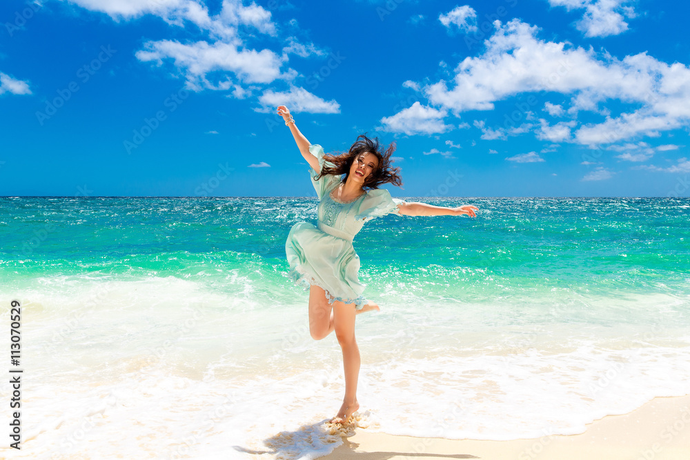 Young beautiful Asian girl in blue dress on the beach of a trop Young beautiful Asian girl in blue dress on the beach of a trop
