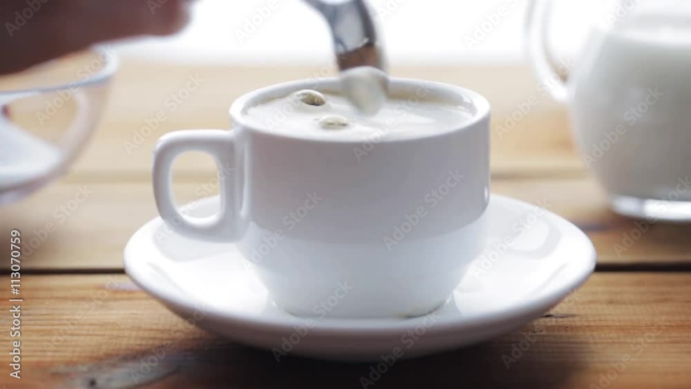 hand pouring sugar by teaspoon into coffee cup hand pouring sugar by teaspoon into coffee cup