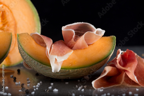 Jambon mix. Ham. Traditional Italian and Spanish salting, smoking, dry-cured dish - jamon Serrano and prosciutto crudo sliced with melon on grey background. Copy space. Closeup.