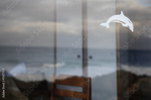 View of rough sea through window with dolphin decal on it