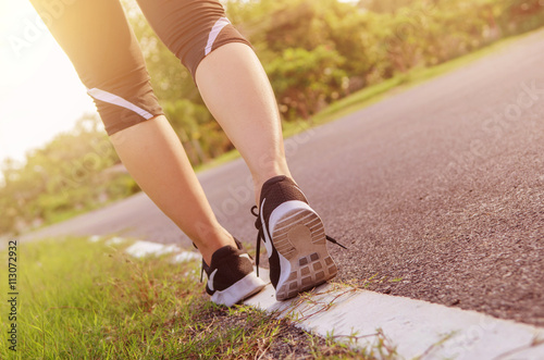 Closeup on shoe athlete runner feet running on road. woman fitness jog workout wellness concept at sunrise morning.