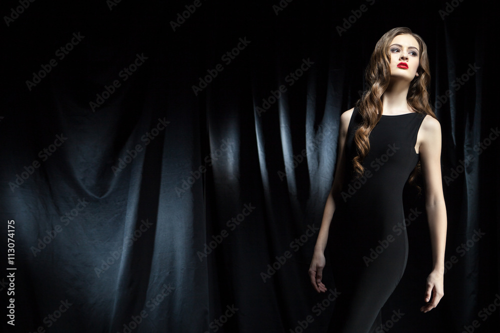 elegant woman with long wavy hair against of black cloth