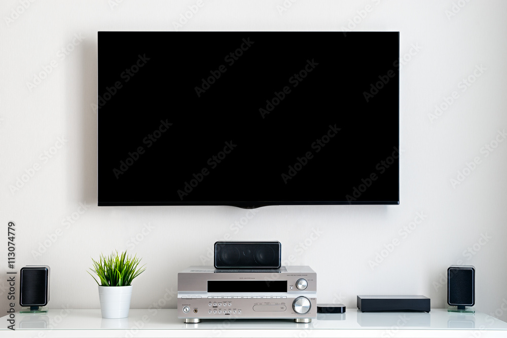 Home multimedia center - flat tv with blank black screen on wall and acoustic system in residential room interior