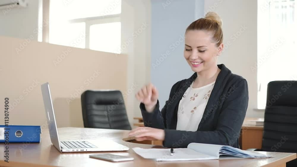 Office worker smiling and working on a laptop. Office worker smiling and working on a laptop.