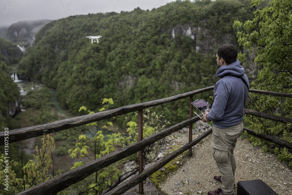 Man is operating the drone with a Plitvice waterfalls background