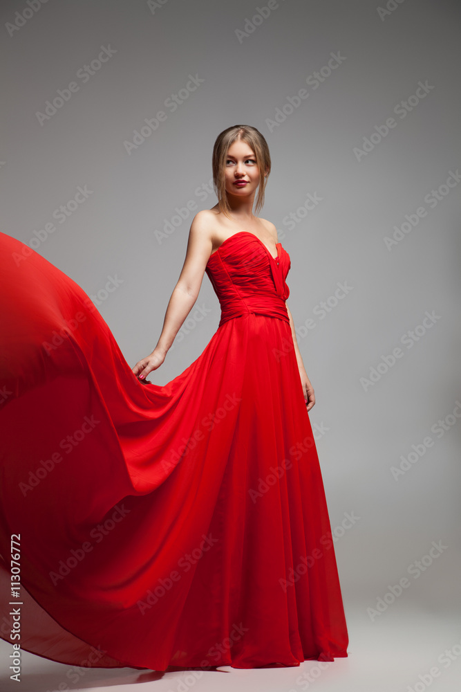 Beautiful model in red dress with flying skirt
