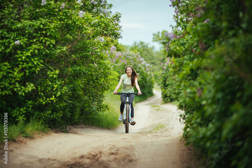 Happy girl cyclist riding on a mountain bike outside. Adventure travel. © deineka