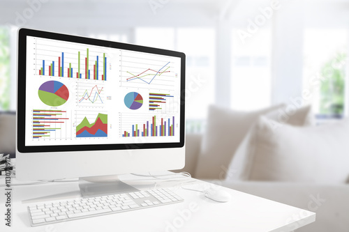 Modern computer with keyboard and mouse on table showing charts photo