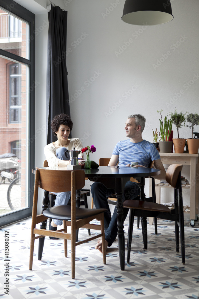 A cheerful hip mixed age couple enjoying breakfast together in their dining room A cheerful hip mixed age couple enjoying breakfast together in their dining room