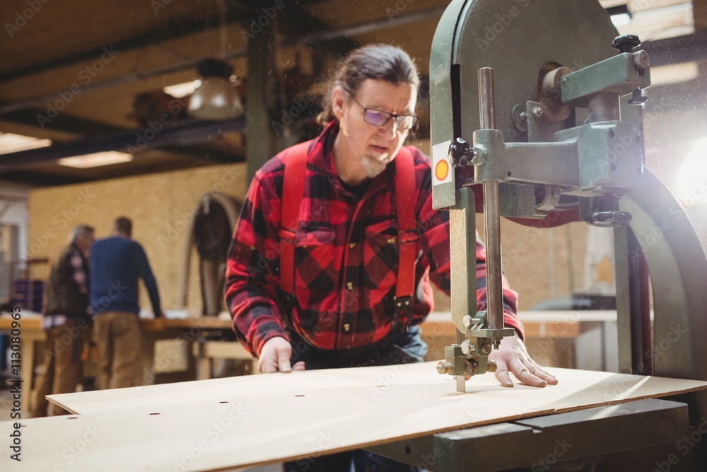 Carpenter sawing a plank of wood Carpenter sawing a plank of wood